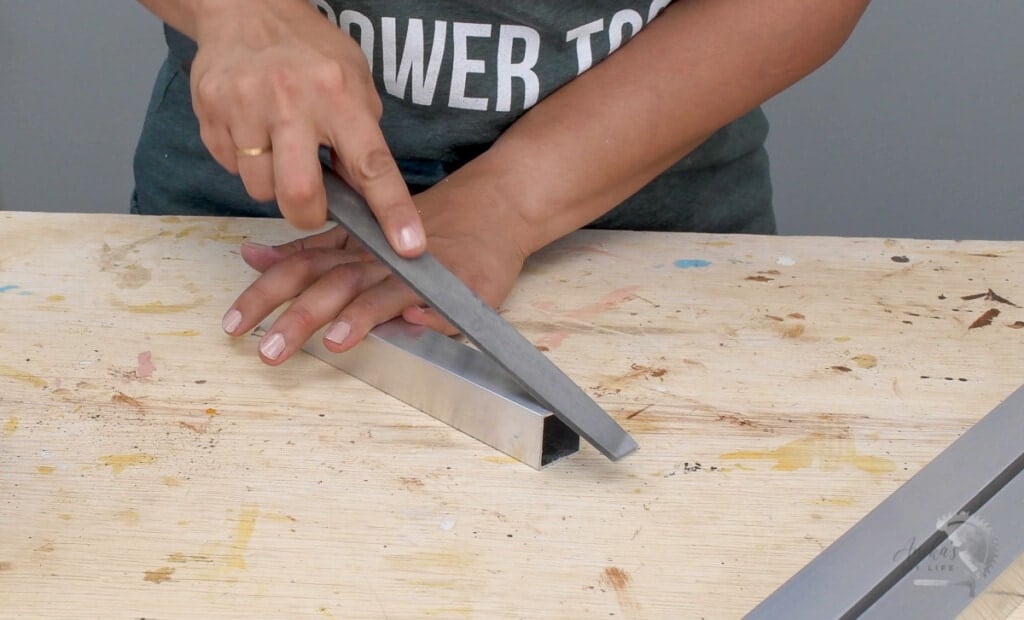 Woman filing the edge of an aluminum tube with a metal file.