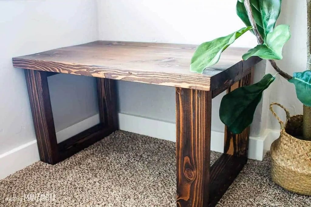 wood bench sitting next to a plant in a basket