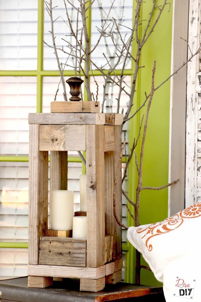 Wooden lantern made from scrap 2x4s with candles sitting in it in front of a window