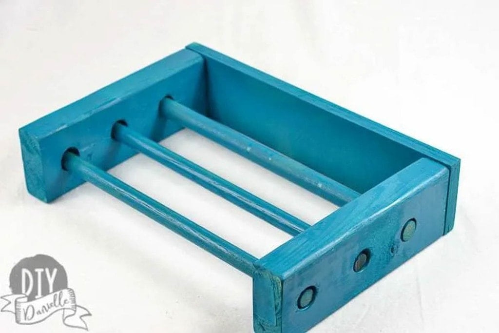 Turquoise painted organizer for kitchen wrap made from scrap 2x4s and dowels
