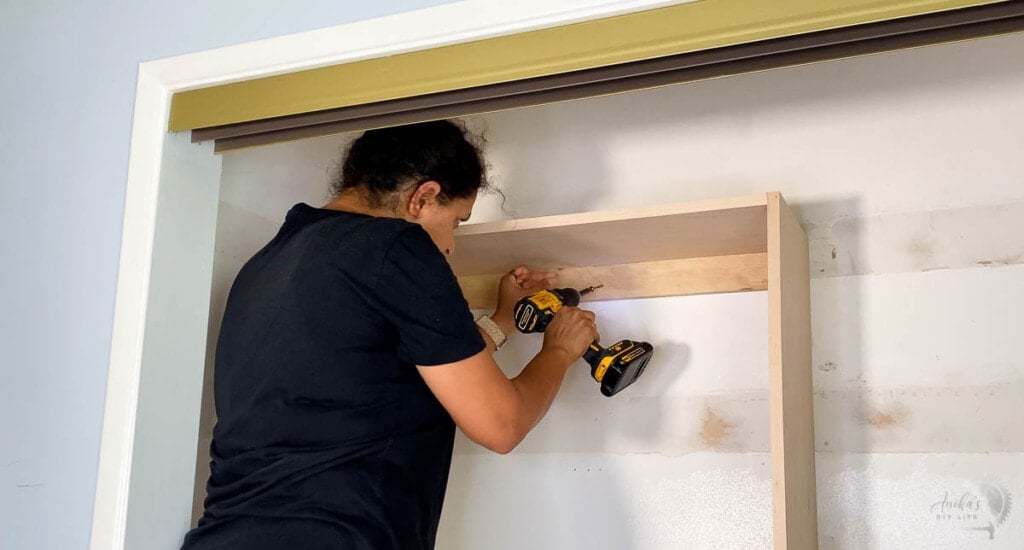 woamn attaching closet organizer to the wall with cabinet screws