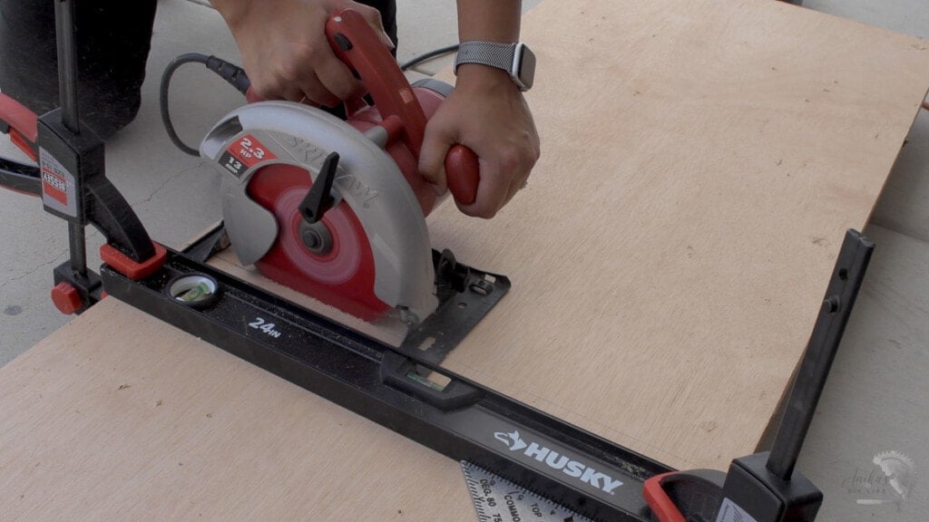 woman making the cut on a sheet of plywood using a circular saw