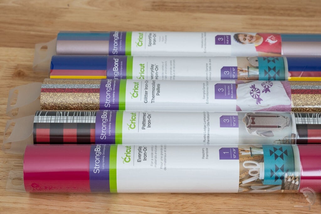 rolls of various types of Cricut Iron-on Vinyl on a table