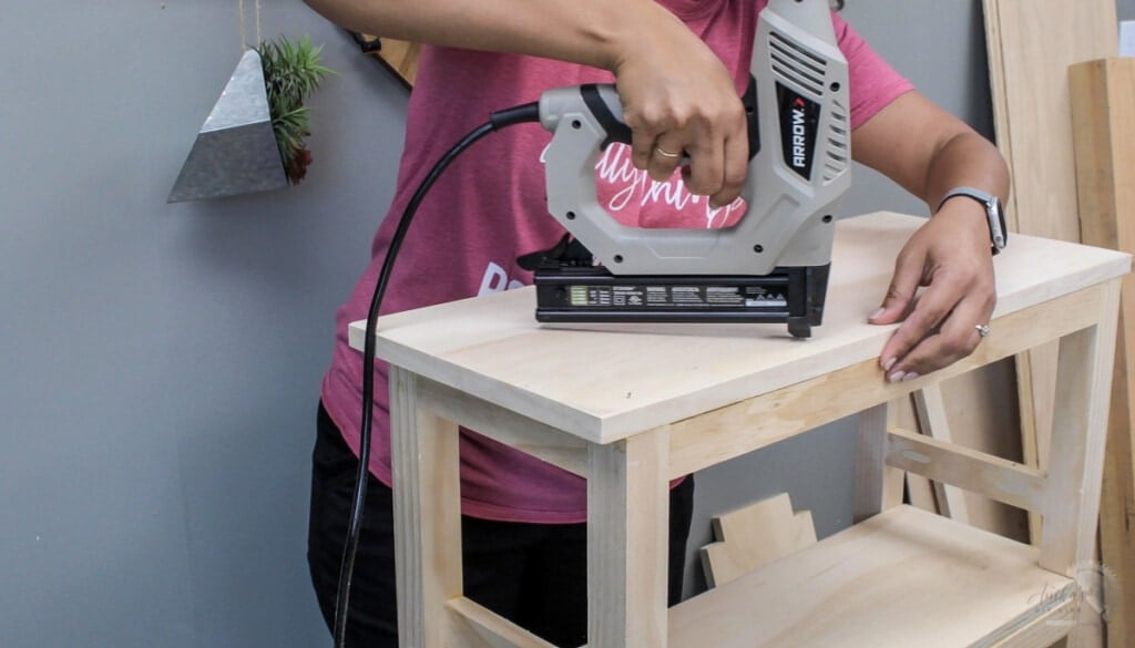 Woamn attaching the top of the easy DIY bookshelf