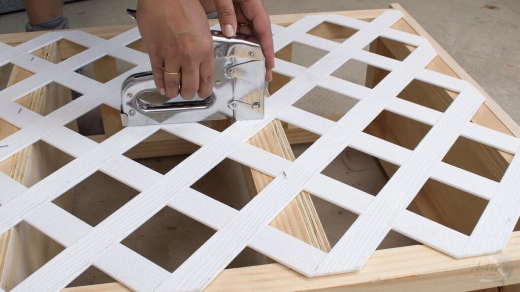 close up of staple gun attaching trellis to the bookshelf