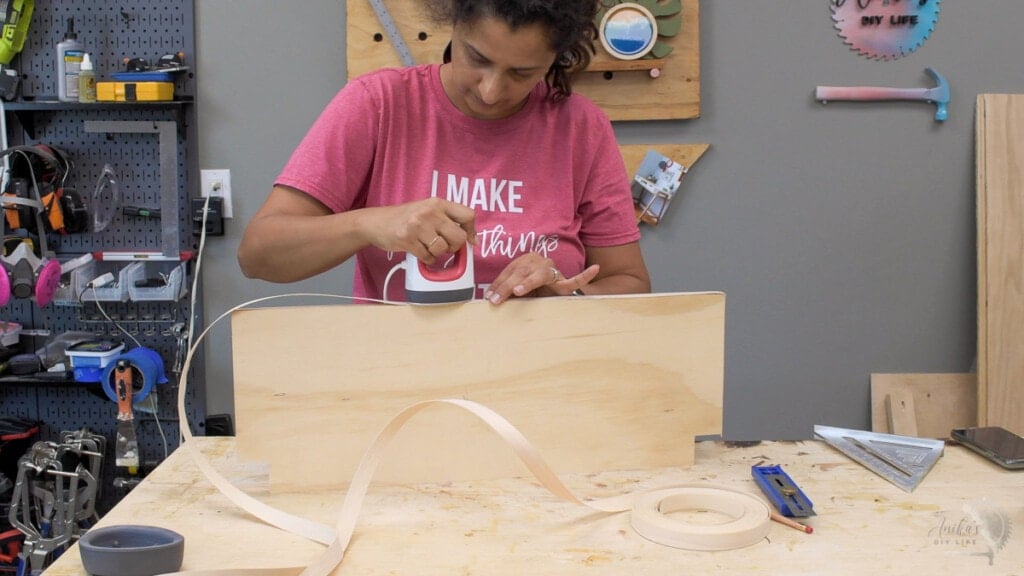 woman applying edge banding to a sheet of plywood