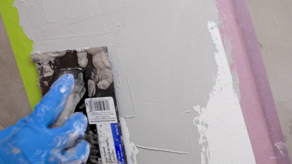 Woman applying a lighter colored cement to the wall