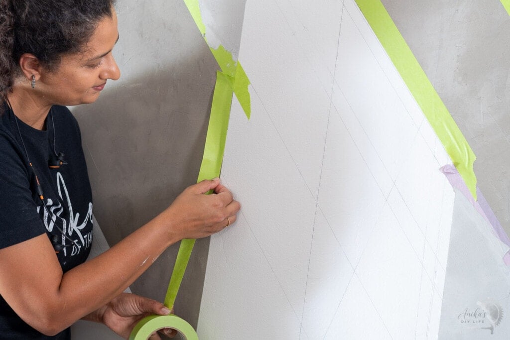 Woman applying tape to the concrete wall for a gorgeous accent wall
