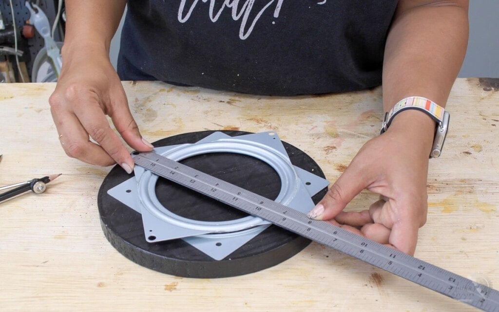 woman measuring the distance between the holes on lazy susan hardware to install them