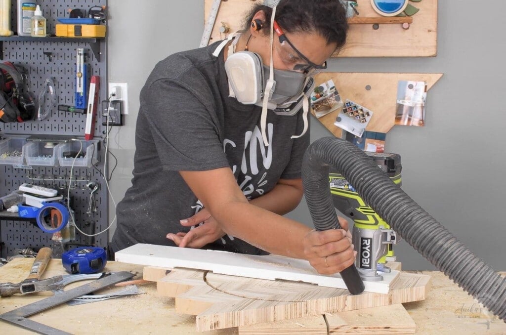 woman using a homemade palm router jig. to cut a circle in patterned plywood