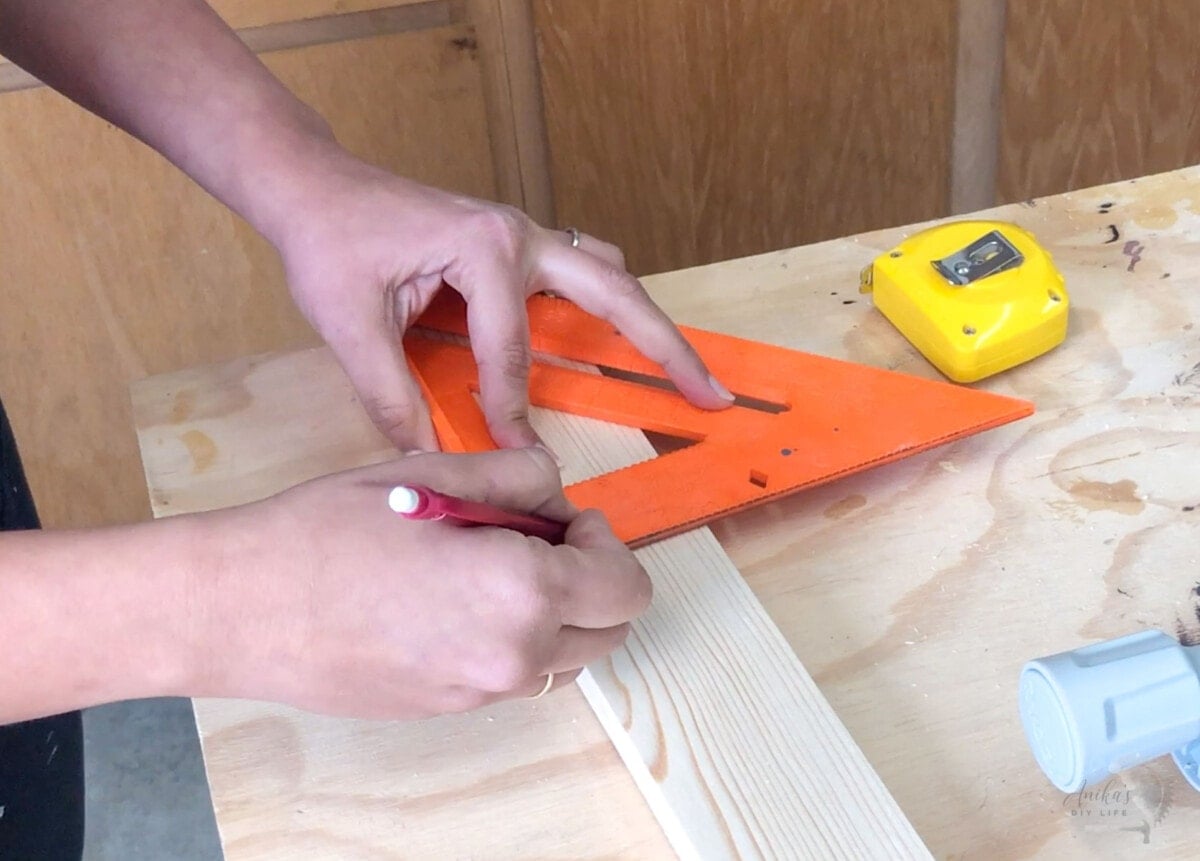 woman marking the cut line on a board using a speed square