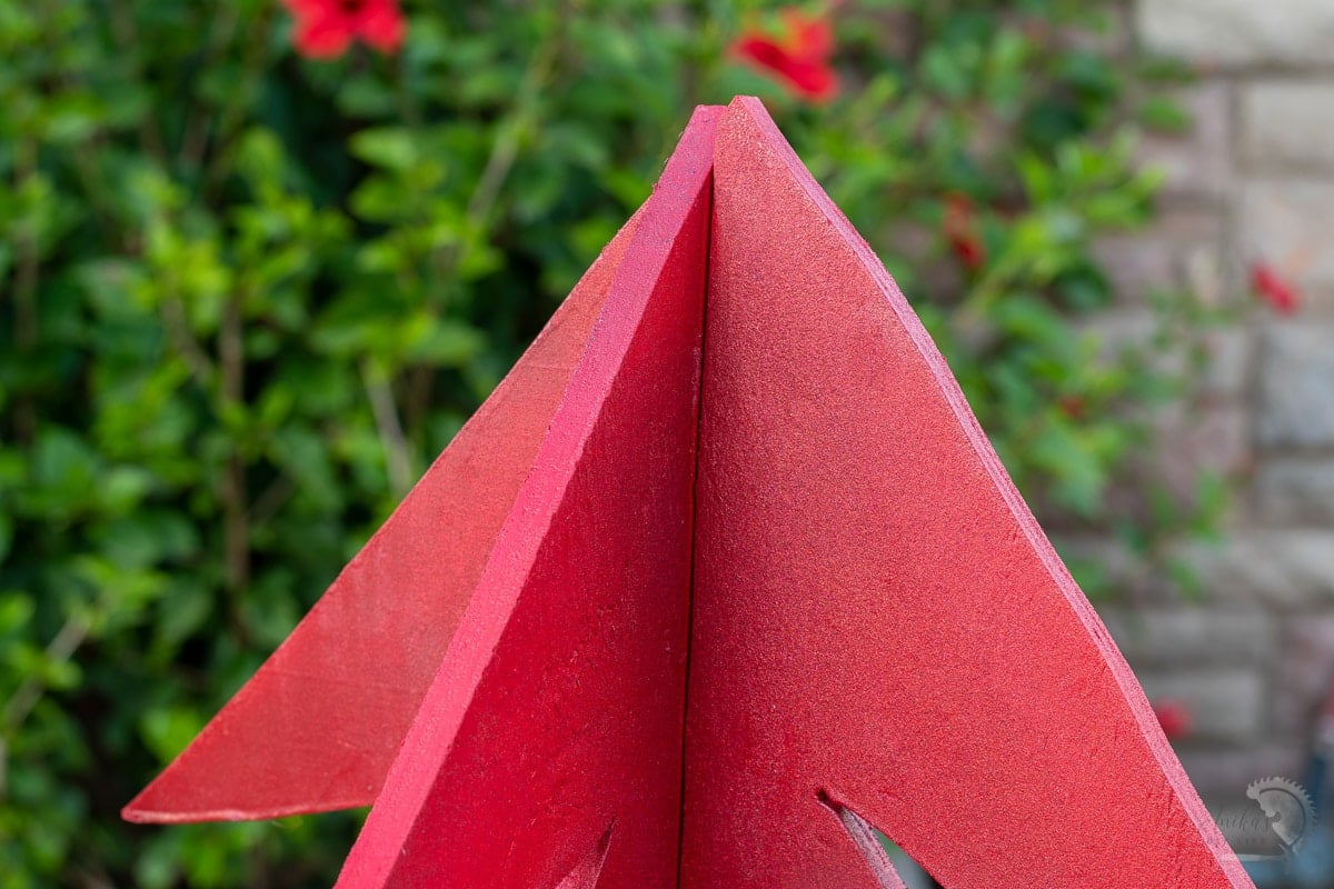 close up of red glitter paint on DIY plywood Christmas trees in yard