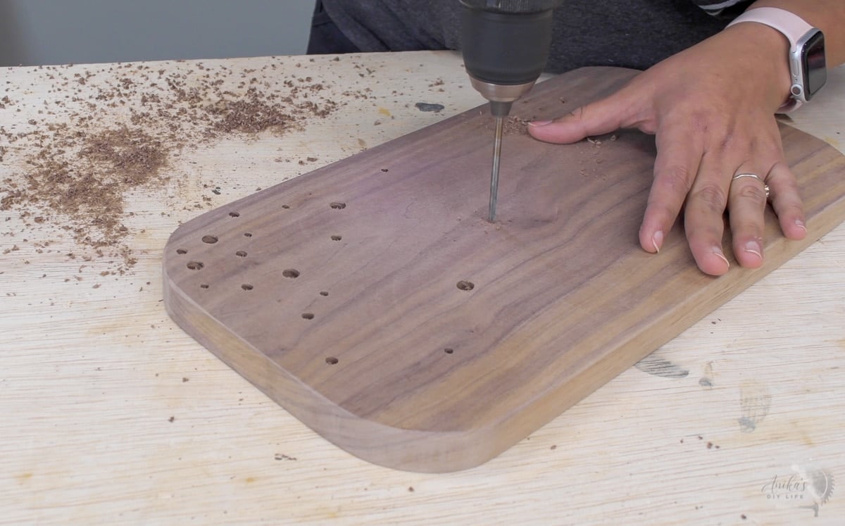 woman making holes to add the brass rod inlays.