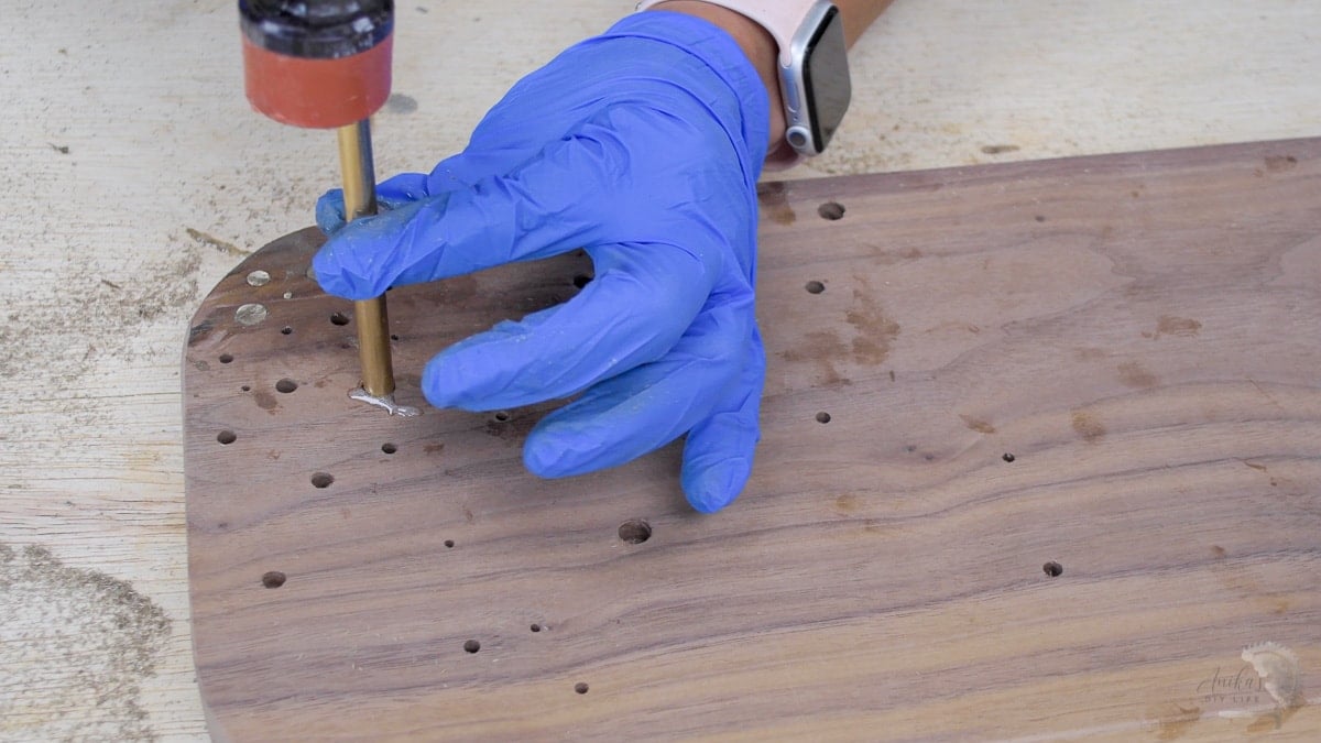 woman adding brass rod inlay into walnut.