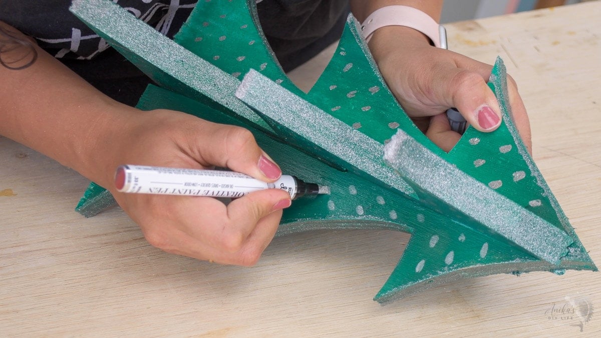 woman draing patterns on DIY wood Christmas trees using a paint pen