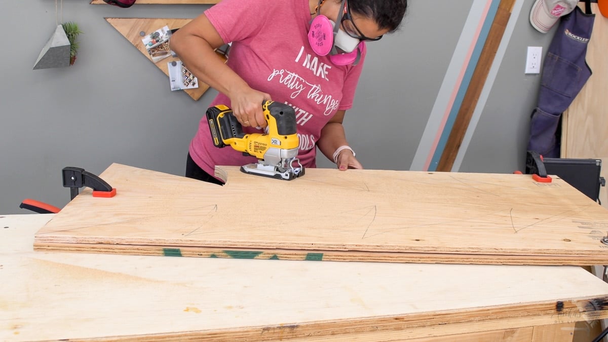 Woman cutting out the Christmas tree from plywood using a jigsaw