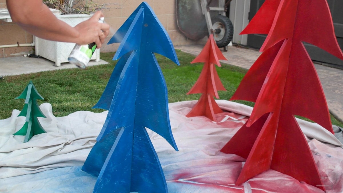 Woman applying glow in dark spray paint to the Christmas Tree