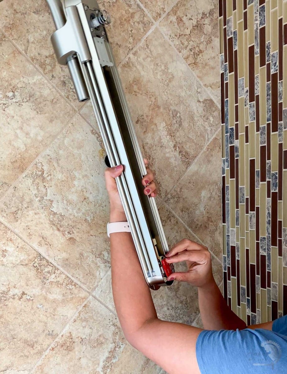 woman removing the backing from the adhesive tape of the Nebia by Moen
