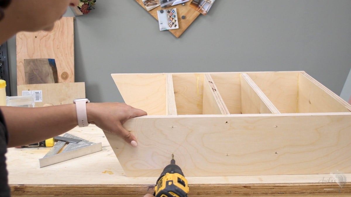 woman attaching shelves in sandpaper organizer with screws.