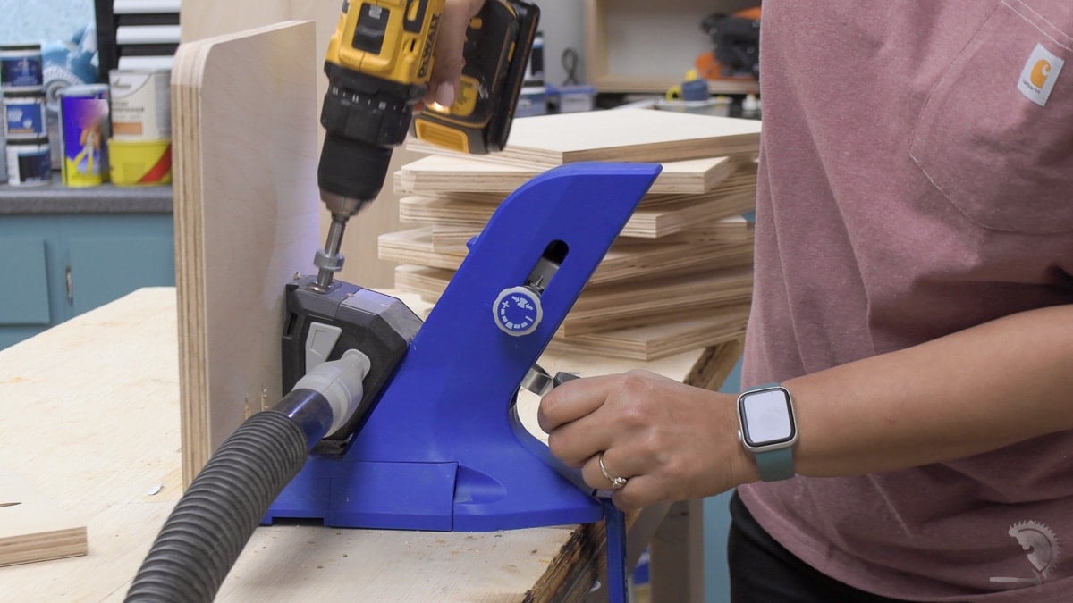 Woman making pocket holes in plywood using a pocket hole jig