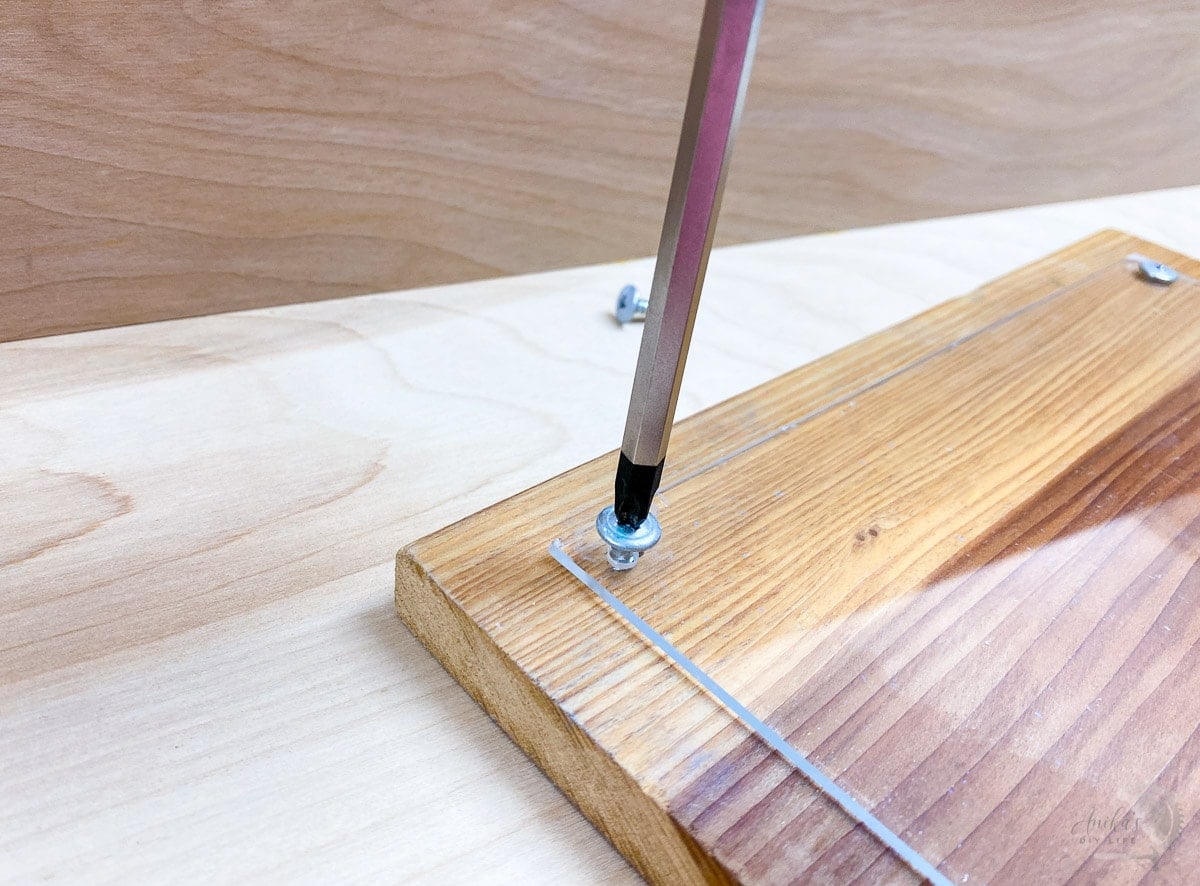 Attaching plexiglass to wood using a screw driver to make a meal planning board