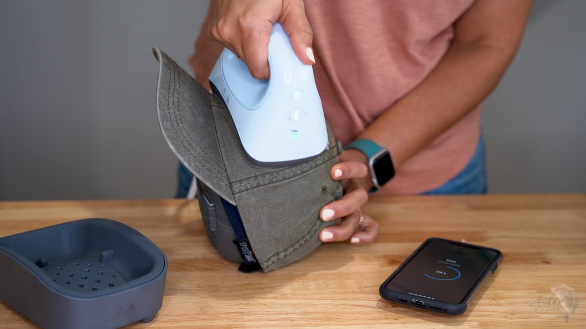 Woman applying heat transfer to a green hat using the hat press