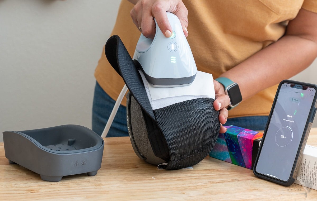 woman applying heat to the hat on hat form using the hat press with countdown timer on phone app