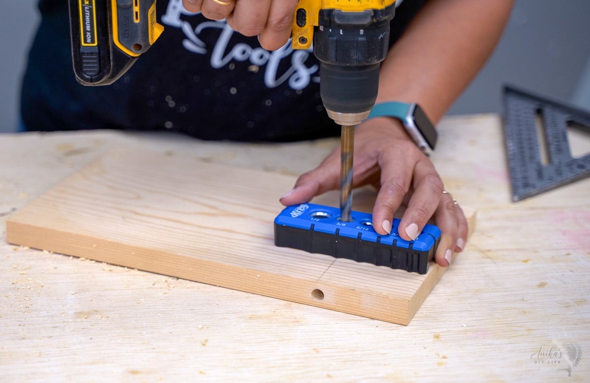 Woman drilling hole into the surface of a board using the drilling guide