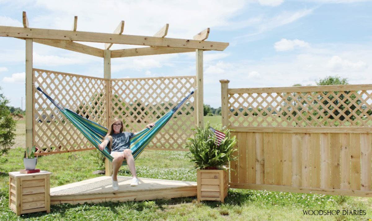 Woman sitting on hammock on deck with pergola
