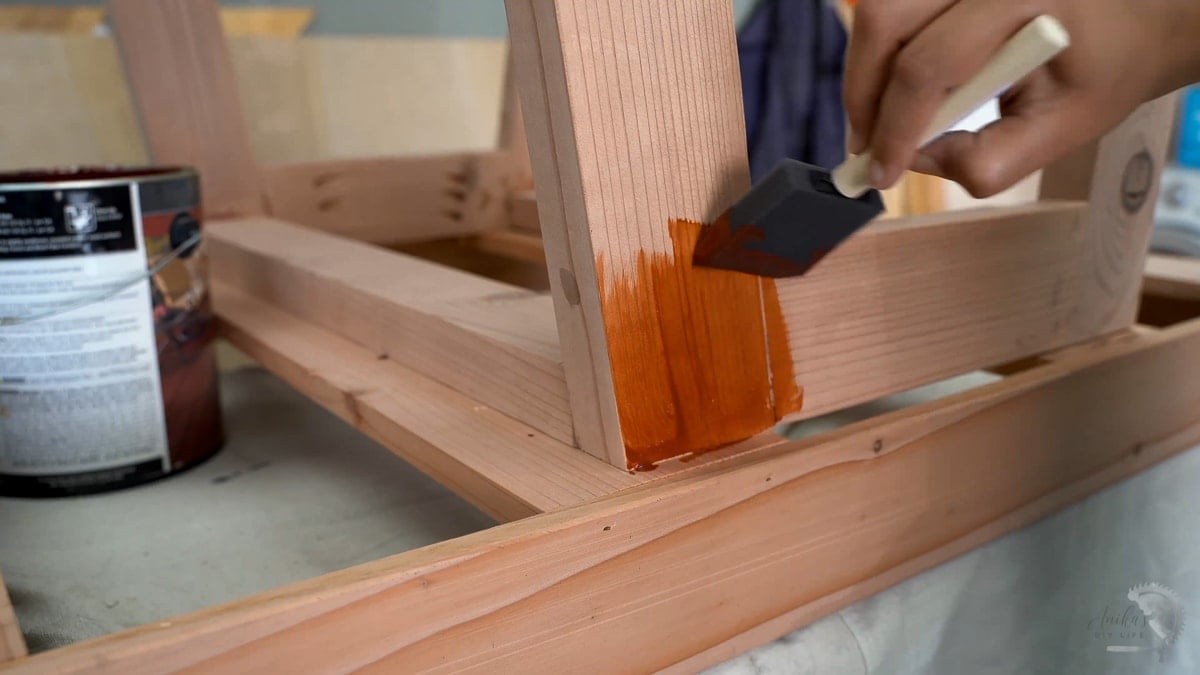 Applying redwood stain to the DIY potting bench