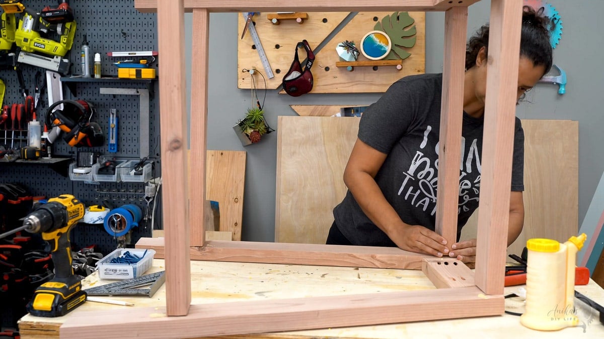 woman attaching the legs supports to build the leg frame for the potting bench