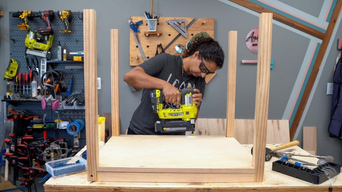 Woman attaching the plywood with a nail gun.