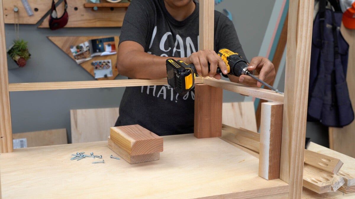 Attachinf the next level of shelves using scrap wood spacers.