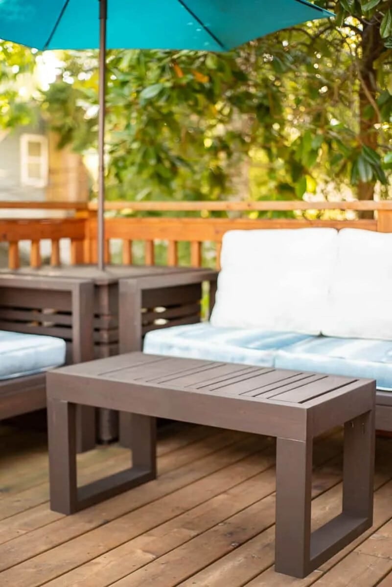 DIY 2x4 outdoor coffee table sitting in front of outdoor couch and loveseat