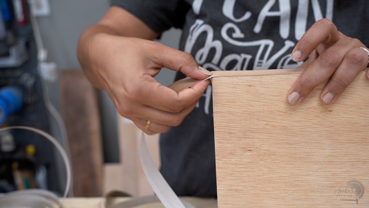 Woman breaking off edge banding at the end of the edge