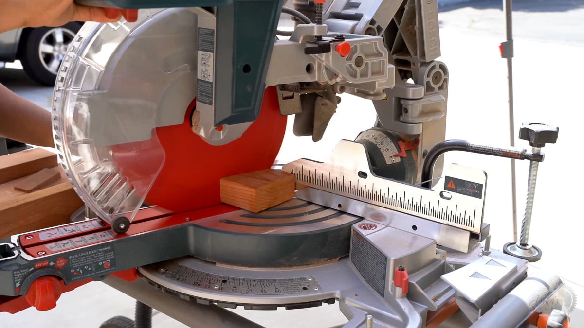 woman cutting 2x4 redwood at an angle on miter saw