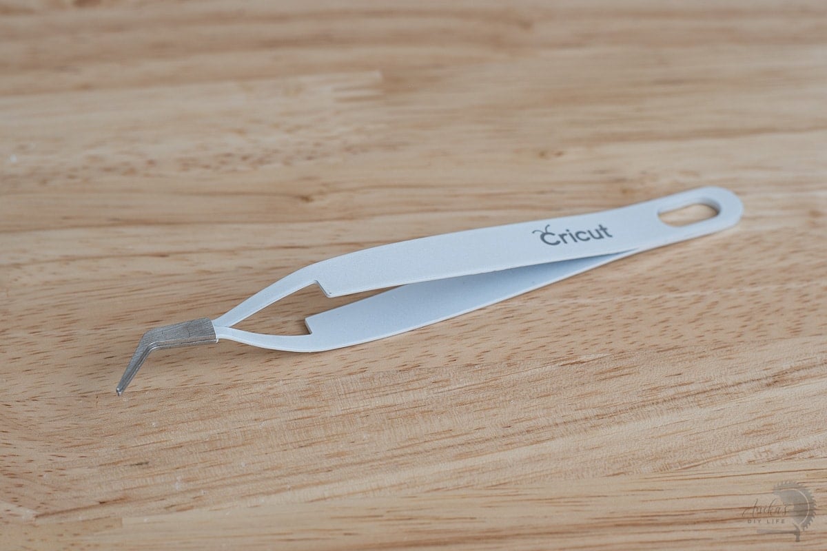 Cricut reverse tweezers on the wood desk