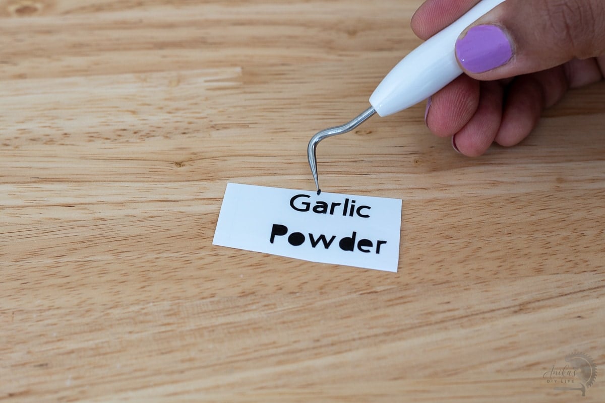 Woman using Cricut weeding tool to remove black spot from decal
