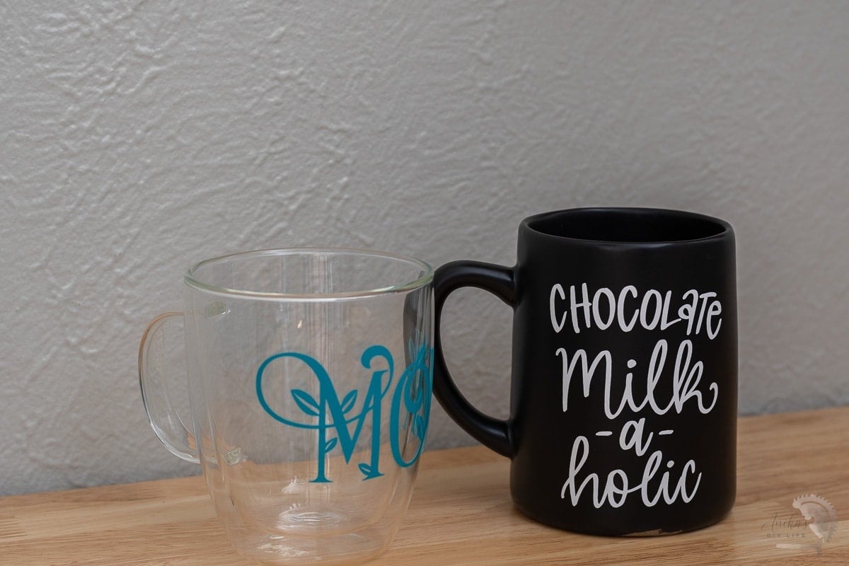 Clear mug with blue vinyl and black mug with white vinyl on table