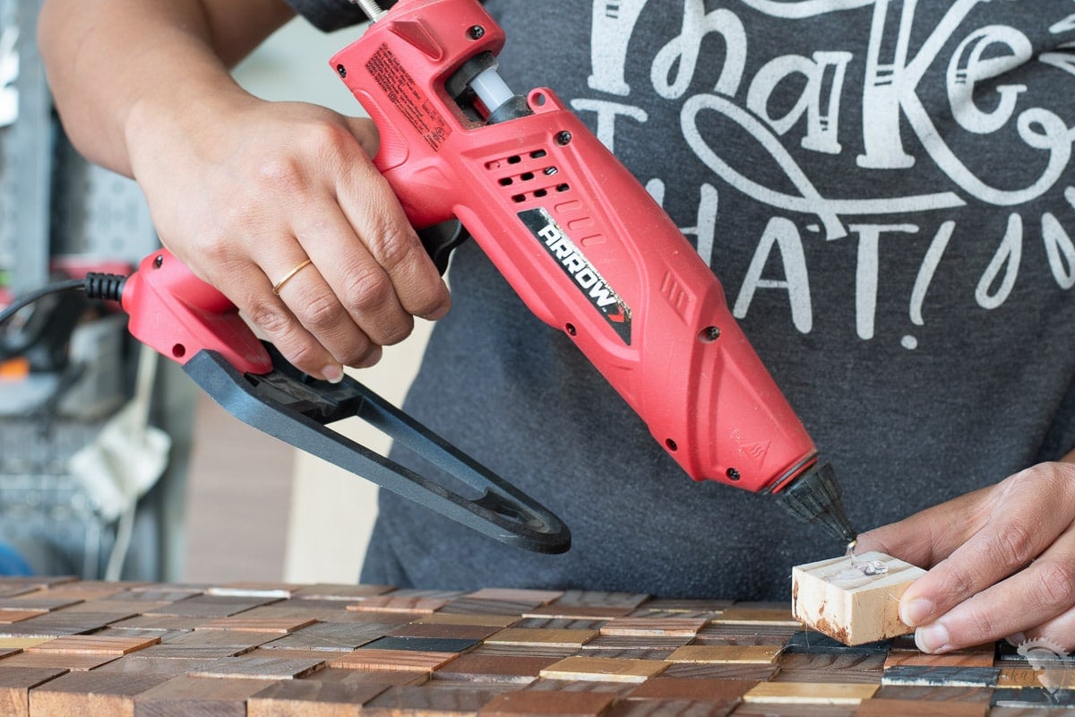 Woman using Arrow glue gun to apply hot glue to block