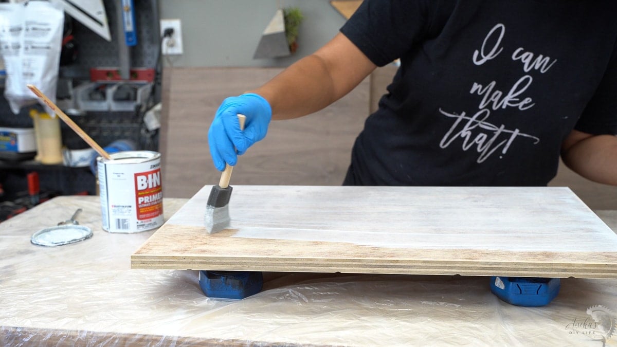 Applying primer to plywood board
