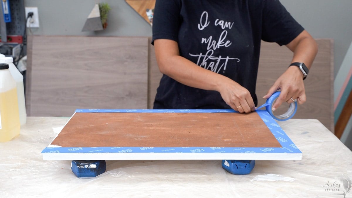 Applying masking tape to back of plywood board for epoxy marble