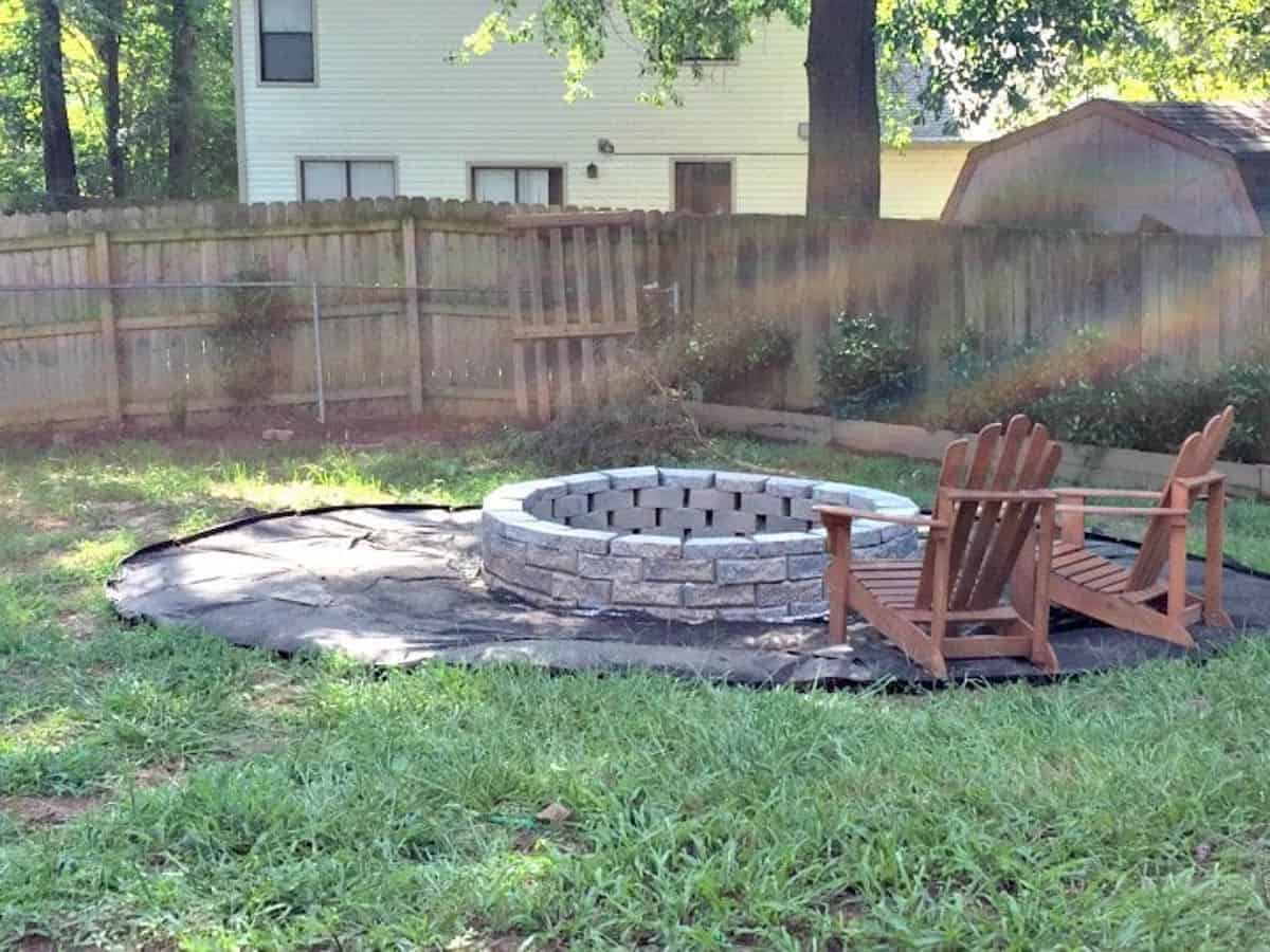 large fire pit in the backyard with two adirondack chairs