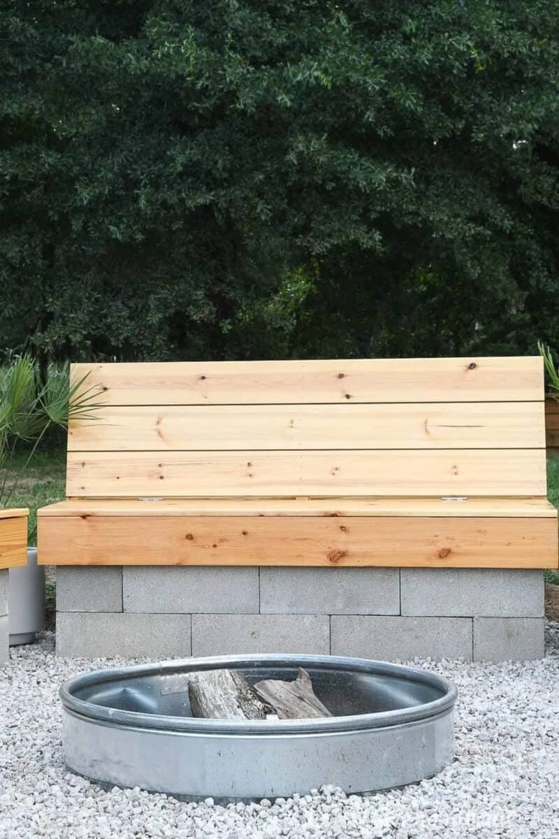 Fire pit ring in the ground with wood bench with concrete block base