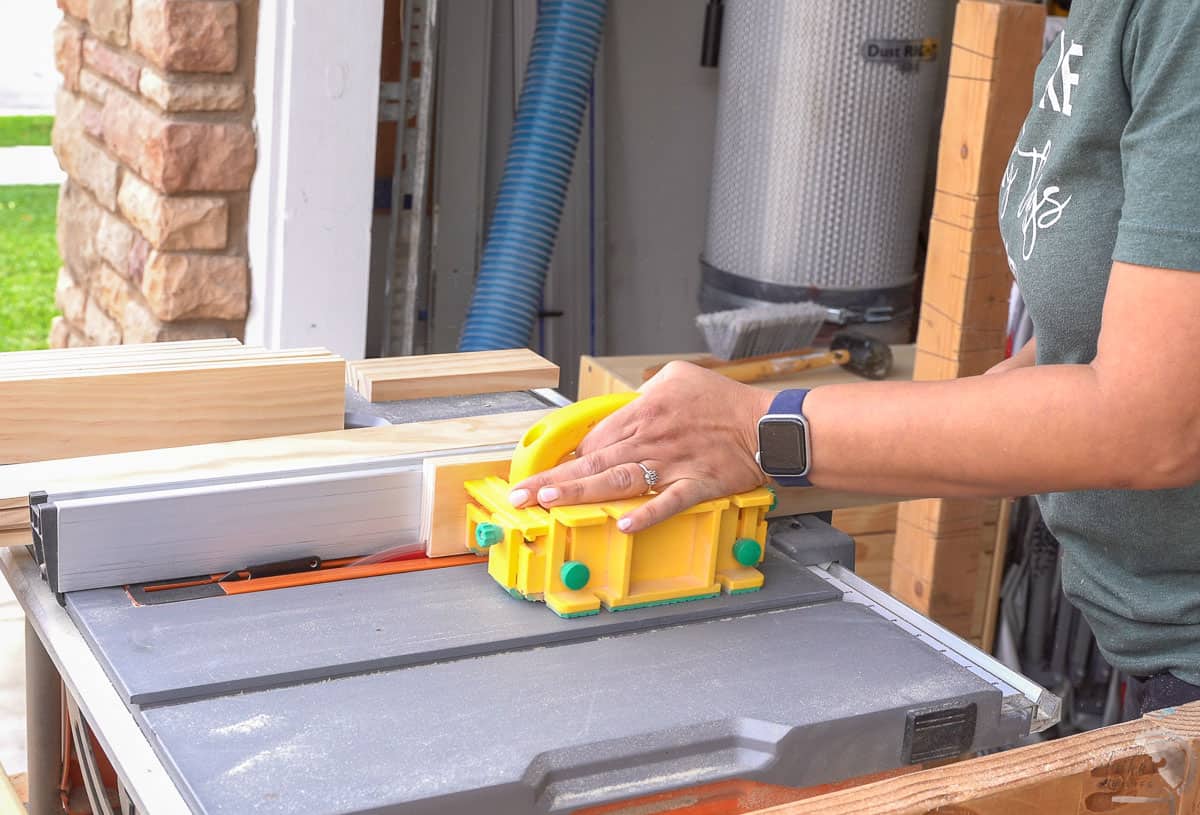 Woman running boards through the table saw to make a groove for the shaker style doors.