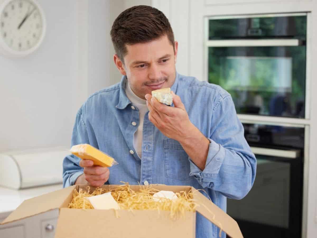 Man unpacking subscription box of cheeses