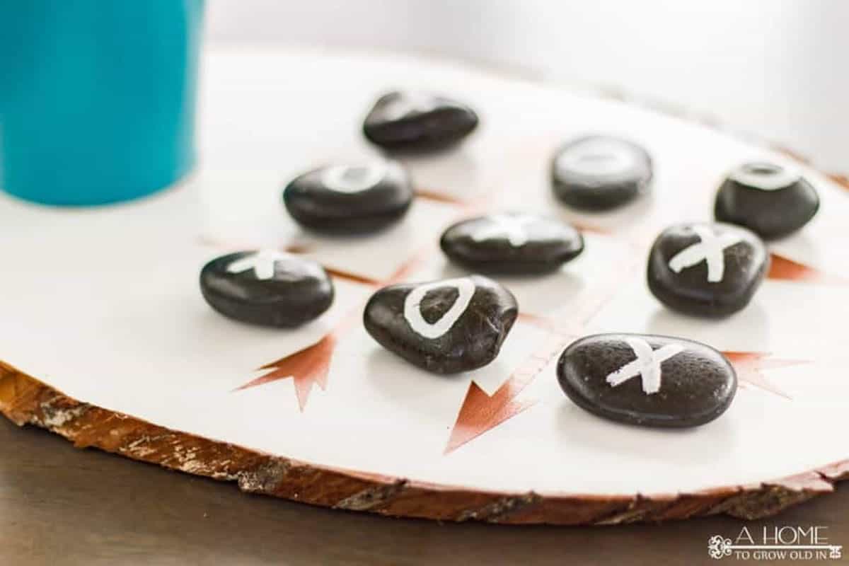 tic tac toe game board made from wood slice and stones