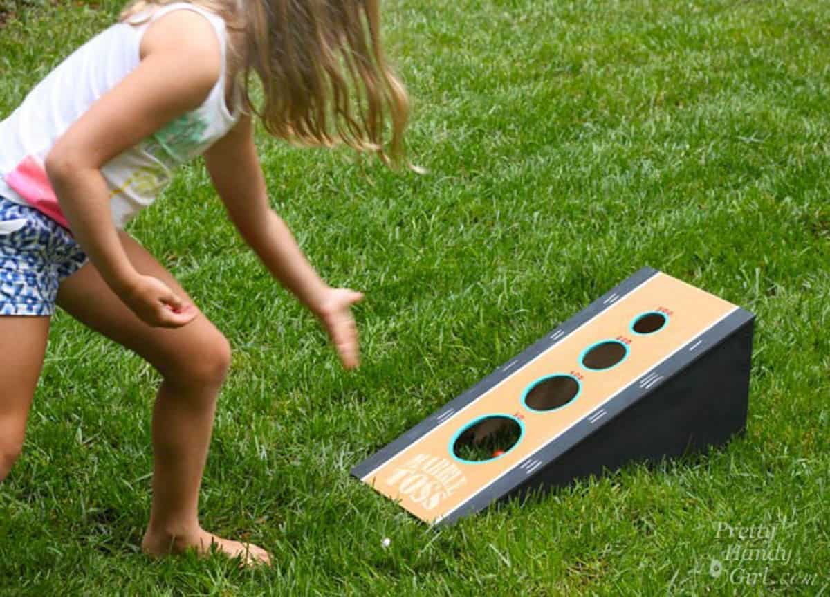 Young girl playing DIY yard game marble toss