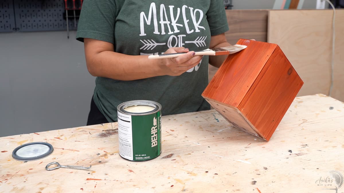 woman applying spar urethane to the vase and planter