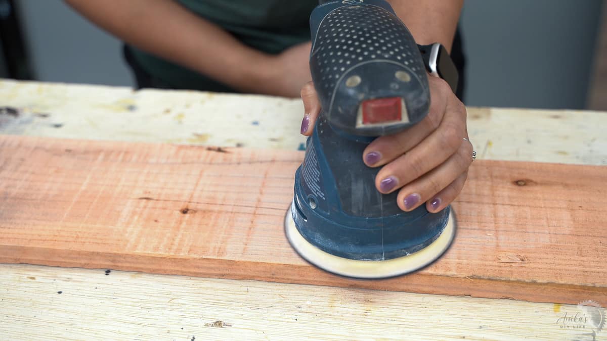 Woman sanding redwood board with a sander